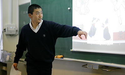 電子黒板の前に立ち、説明を行っている生徒。
