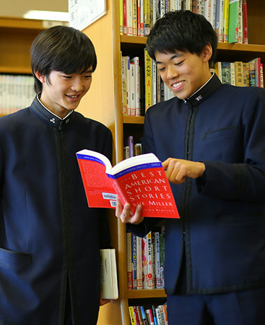 図書館で本を見ながら談笑する男子生徒二人